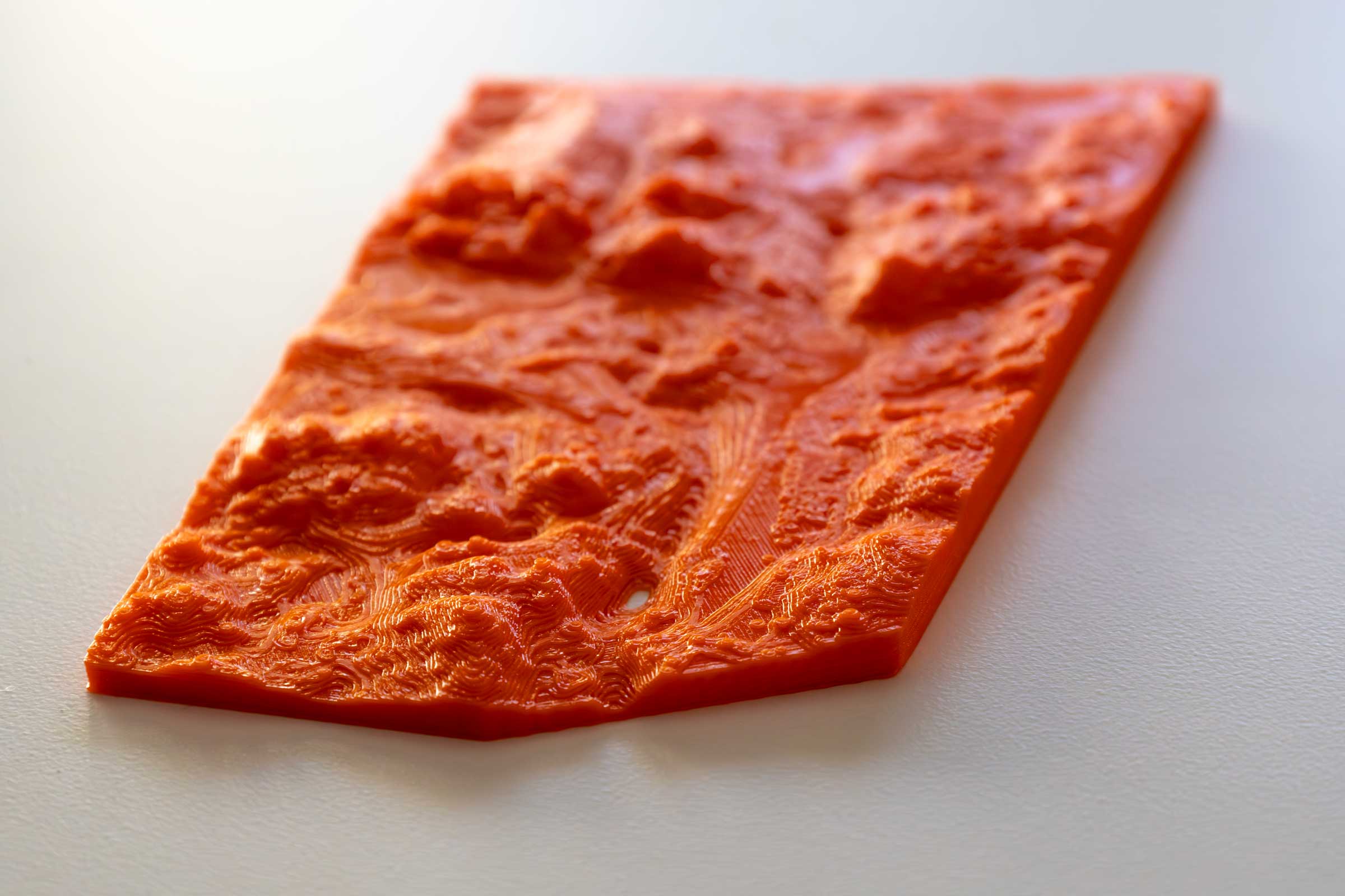 An orange 3D printed terrain with a hole in it